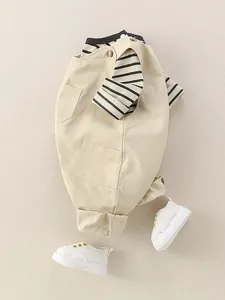 Ensemble bébé de printemps avec salopette en coton beige et haut à rayures noires