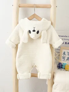 White plush baby romper with animal hood hanging on a wooden ladder in warm setting