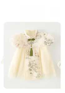 Détail d'un barboteuse chinoise pour bébé avec imprimé floral et glands verts décoratifs