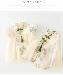 Détails de la robe chinoise pour bébé avec motifs de jardin et pompons verts