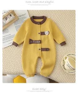 Close-up of yellow knit baby romper with brown trim and cute cartoon bear embroidery