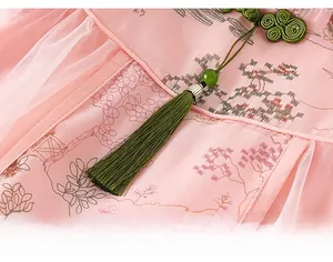 Détail d'une robe chinoise rose avec boucle traditionnelle et pendentif à pompon vert