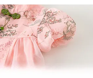 Détail de robe chinoise rose avec imprimé floral, bouton vert et manches bouffantes