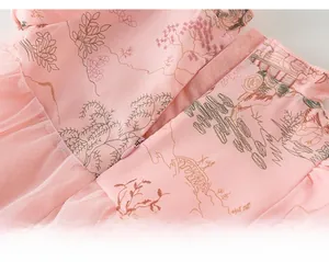 Détail de robe rose pour bébé avec motifs de paysages et fermeture éclair invisible