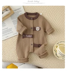 Detail of warm brown knitted baby romper featuring a cute teddy bear embroidery patch