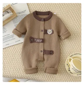 Detail of baby knit romper showing brown ribbed fabric, teddy bear embroidery and buttons