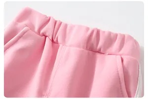 Détail de la taille du jogging rose avec élastique, poches et bandes blanches