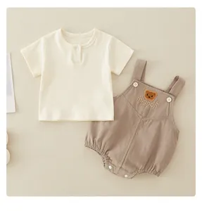 Detail of baby cotton two-piece set featuring embroidered brown bear and mignon text