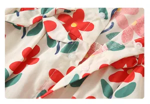 Detail eines Baby-Stramplers mit roten Blumenprints und transparenten Druckknöpfen
