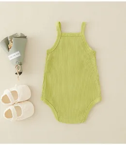 Detail eines grünen gerippten Babybodys mit Trägern und weichem dekorativem Zubehör