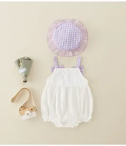Detailed flat lay of white cotton baby bodysuit with purple plaid bows and matching sun hat