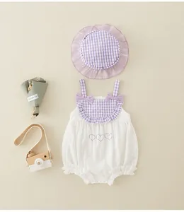 Flat lay of white and purple plaid baby romper with matching sun hat and heart embroidery