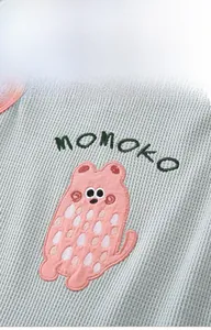Detail of baby waffle knit fabric with cute cartoon bear embroidery and MOMOKO lettering