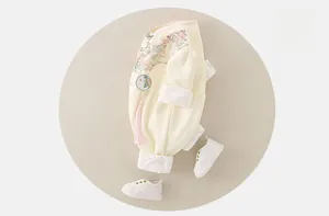 Détail d'un body chinois pour bébé avec motifs floraux et décorations à pompons roses