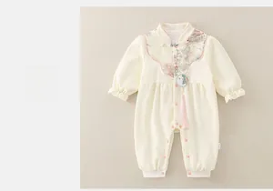 Détail de barboteuse bébé avec imprimé montagne chinois, boutons chinois et gland rose