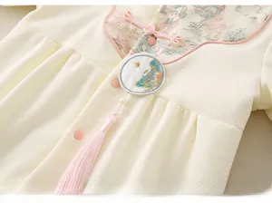 Détail de la grenouillère bébé avec bouton chinois et broderie de paysage de montagne