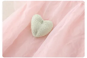 Nahaufnahme von rosa Tüllstoff mit grünem Herz-Aufnäher-Detail am Mädchen-Sommerkleid
