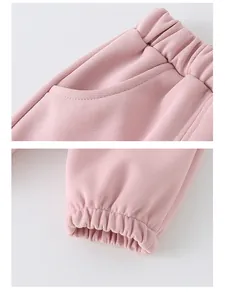 Detail of pink cotton joggers featuring elastic waist with side pockets and cuffed hems