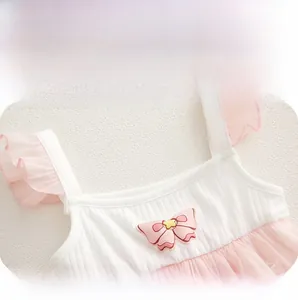 Detail of baby bodysuit featuring white ribbed fabric, pink mesh ruffles, and a bow accent