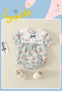 Detail von Baby-Baumwoll-Strampler mit Erdbeerprint, Stickkragen und weißen Schuhen