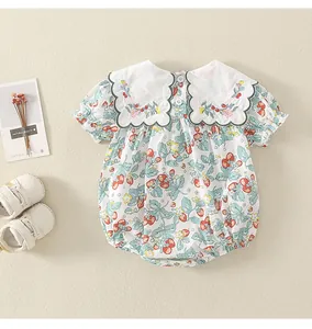 Detail eines Baby-Bodys mit Erdbeermuster, Blumenstickerei und weißem Kragen
