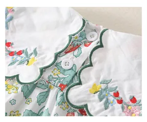 Detail eines Baby-Bodys-Kragens mit Erdbeerstickerei und grünen Bogenkanten