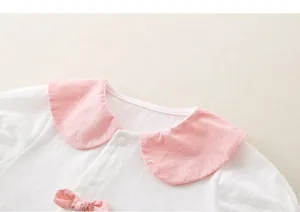 Detail von Baby-Strampler mit rosa Peter-Pan-Kragen und Schleife auf Pointelle-Baumwolle