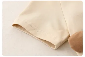 Detail of short sleeve cuff with double stitching and a brown plush animal ornament