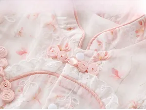 Detail of pink floral infant romper featuring Chinese collar, lace trim, and pearl button