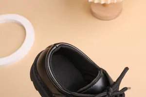 Close-up of boys black leather shoes featuring padded heel and breathable mesh lining
