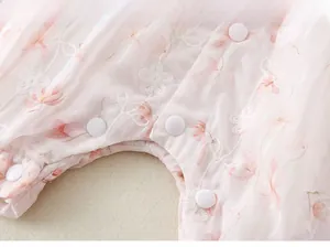 Detail of pink newborn romper with floral embroidery and white snap buttons