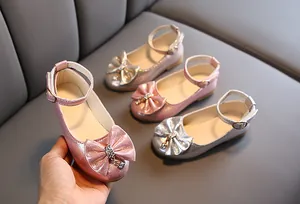 Close-up of glitter girls' Mary Jane shoes with bow decoration and rhinestone charms