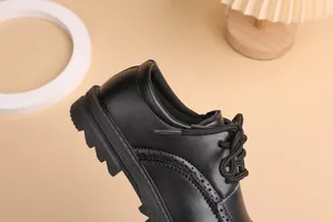 Detail of boys black brogue leather shoes with lace-up design and thick rubber sole