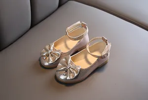 Detail of girls champagne glitter Mary Jane shoes with bow and crystal pendant