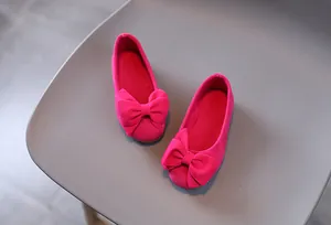 Dettaglio di scarpe da bambina in camoscio rosso rosa con fiocco grande e punta rotonda