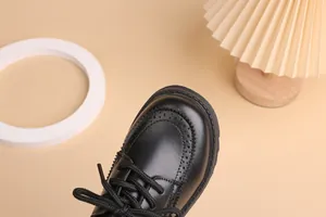 Close-up of boys black leather brogue shoes with classic wingtip carving details