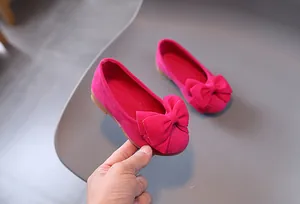 Dettaglio delle scarpe da principessa rosa per bambina con fiocco grande e pelle scamosciata