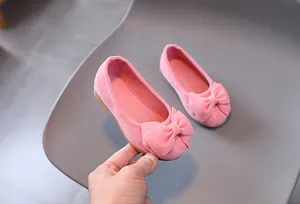 Dettaglio delle scarpe piatte rosa per bambina con fiocco e trama effetto scamosciato