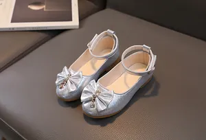 Dettaglio di scarpe Mary Jane argento per bambine con fiocco glitter e nappe