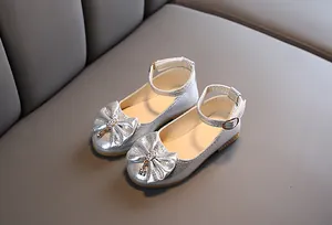 Close-up of silver girls Mary Jane shoes with glitter bow and rhinestone pendant