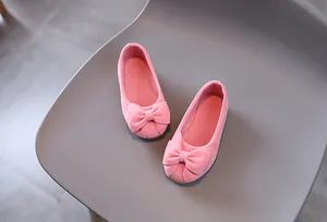 Dettaglio scarpe da principessa rosa per bambina con fiocco e morbida texture scamosciata