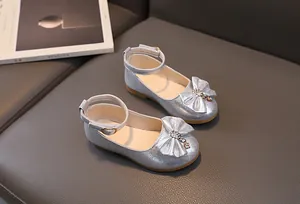 Dettaglio di scarpe Mary Jane argento glitterate con fiocco e ciondolo per bambine