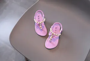 Detalle de sandalias moradas para niña con perlas y lazos brillantes decorativos
