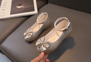 Dettaglio delle scarpe argentate glitter da bambina con fiocco e fibbia alla caviglia
