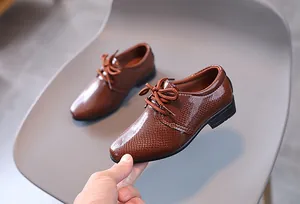 Detail von braunen Schnürschuhen für Jungen mit glänzender Schlangenleder-Prägung