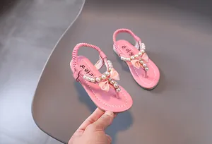 Detalle de sandalias rosas para niñas con lazos de seda y elegantes perlas artificiales