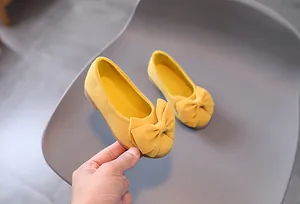 Dettaglio di scarpa piatta gialla in camoscio per bambina con grande fiocco decorativo