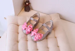 Detailed view of pink sequin girl's princess shoes with a satin bow and wavy edges