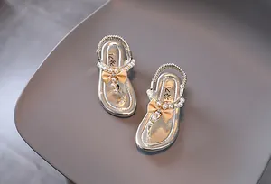 Detalle de sandalias para niña con perlas y lazo de satén en color plateado