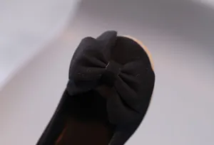 Dettaglio ravvicinato di scarpe nere da bambina con elegante fiocco sulla punta